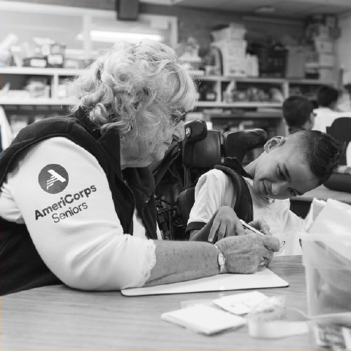AmeriCorps Seniors volunteer helps a student in a classroom.