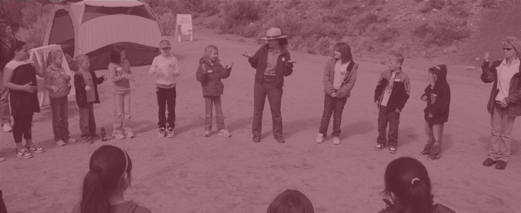 A National Park Service ranger leads a school group in an outdoor desert activity.