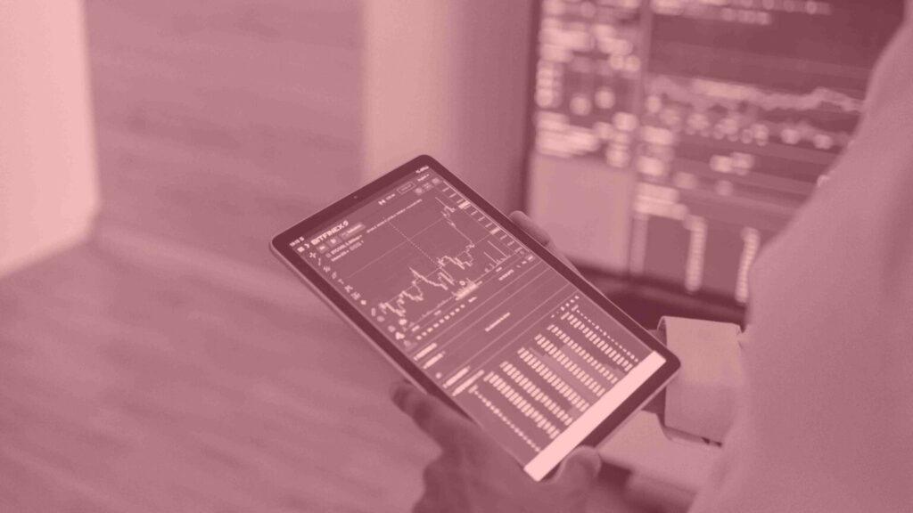 Magenta filtered photo of a person holding a tablet with graphs and charts